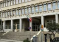 Facciata del Palazzo della Provincia di Ragusa con scalinata, colonne, bandiere e scritta in lettere metalliche sopra l'ingresso