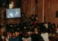 Pubblico seduto in un vicolo a gradini davanti a uno schermo all'aperto durante una serata del cinema di quartiere a Modica