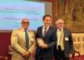 Tre uomini nella Sala della Regina di Montecitorio, quello al centro tiene una confezione di Cioccolato di Modica IGP