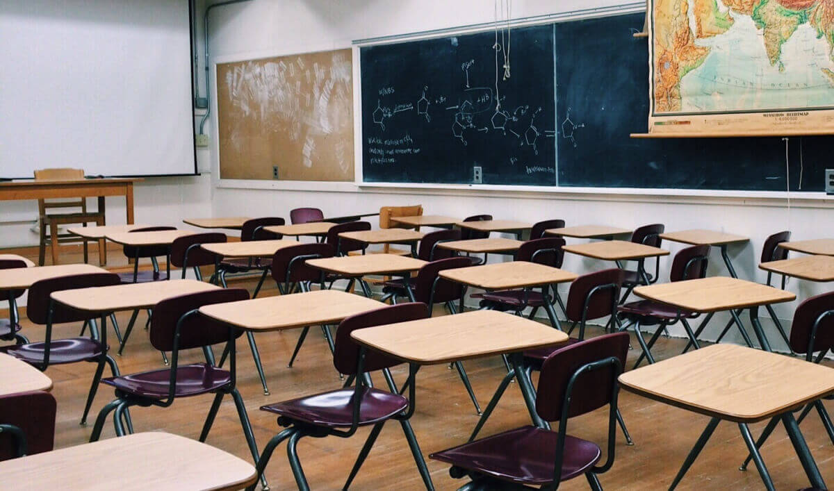 Aula vuota con banchi e un condizionatore a parete, scuole siciliane
