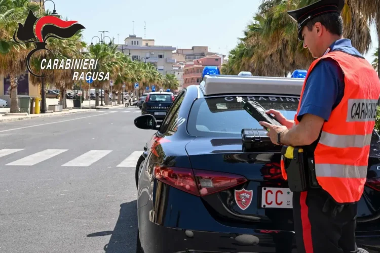 Carabiniere con etilometro accanto a un’auto di servizio durante i controlli dei carabinieri su un viale alberato