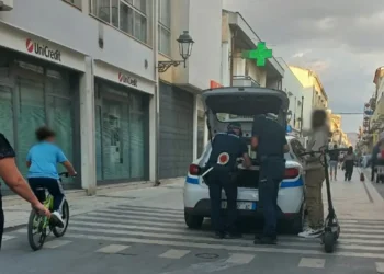Agenti della polizia locale di Vittoria in controllo accanto all'auto di servizio, vicino a un uomo con un monopattino elettrico