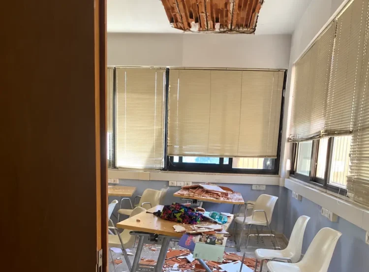 Aula di una scuola di Vittoria con un'apertura nel soffitto crollato e calcinacci su banchi, sedie e pavimento