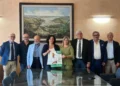 Otto persone in posa in una sala istituzionale di Ragusa mostrano il manifesto sulla donazione degli organi con il QR Code