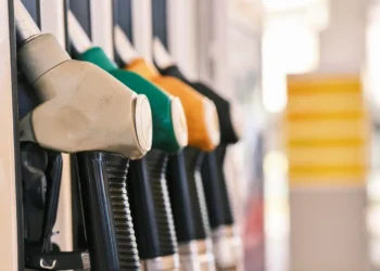 Pistole erogatrici di carburante grigia, verde, arancione e nera allineate su una colonnina di un distributore