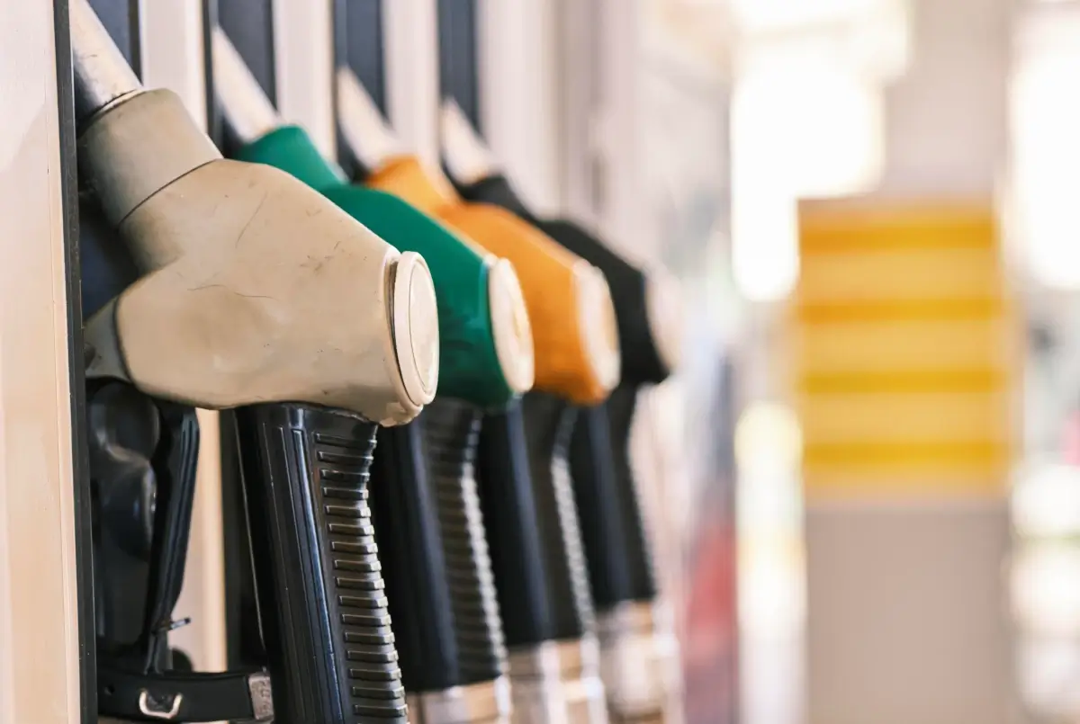 Pistole erogatrici di carburante grigia, verde, arancione e nera allineate su una colonnina di un distributore