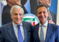 Antonio Tajani e Nino Minardo sorridenti, abbracciati davanti a un manifesto con il logo di Forza Italia