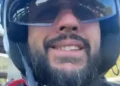 Francesco Nicolosi sorride con casco bianco e occhiali da sole a specchio, inquadrato dal basso durante un giro in scooter