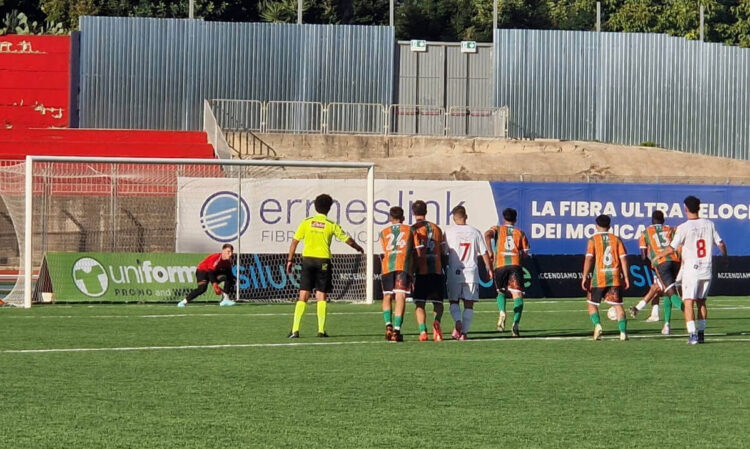 Calcio di rigore in Frigintini Comiso: il portiere in rosso si tuffa, l’arbitro e i giocatori al limite dell’area guardano