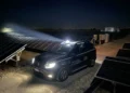 Auto della vigilanza La Sicurezza con il lampeggiante acceso tra i pannelli di un impianto fotovoltaico di notte