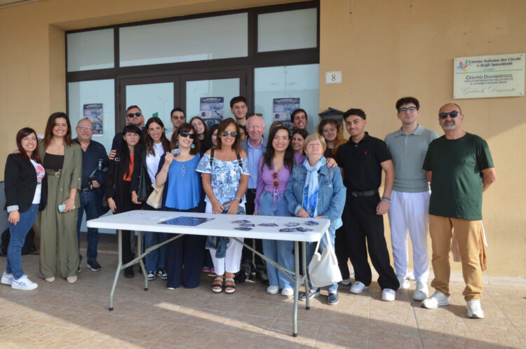 Gruppo di persone davanti al Centro diagnostico Uici di Ragusa per la Giornata mondiale della vista, volantini su un tavolo
