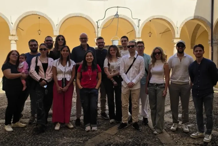 Gruppo di giovani Uici in posa nel chiostro di un edificio storico, con portico ad archi gialli e un pozzo al centro