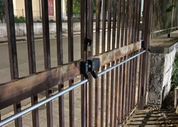 Cancello di un impianto sportivo a Ragusa con maniglione antipanico e lucchetto, affacciato su marciapiede e strada
