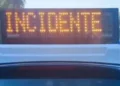 Pannello luminoso arancione con la scritta INCIDENTE sul tetto di un’auto della polizia, con lampeggiante blu