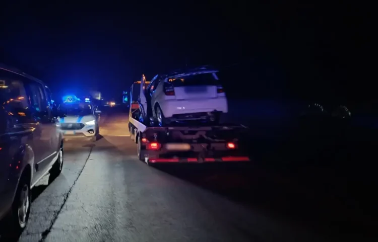 Auto bianca incidentata su un carro attrezzi di notte sulla Sp 16 a Vittoria, dietro una pattuglia della Polizia Locale