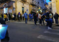 Fedeli lungo una via di Ragusa al passaggio della statua della Madonna del Rosario, con una candela accesa in primo piano