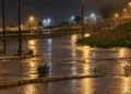 Maltempo a Ragusa: rotatoria e carreggiate allagate di notte, illuminate dai lampioni, con serre e capannoni sullo sfondo