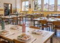 Mensa scolastica a Modica con vaschette di plastica sigillate sui tavoli. Immagine generata con intelligenza artificiale.