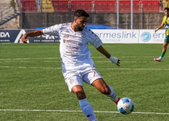 Calciatore del Modica con la maglia bianca numero 23 calcia il pallone durante la partita contro l'Enna, in maglia gialloverde