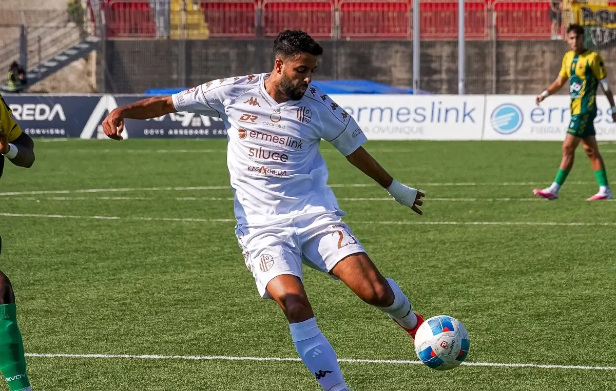 Calciatore del Modica con la maglia bianca numero 23 calcia il pallone durante la partita contro l'Enna, in maglia gialloverde