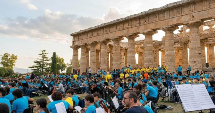 Studenti con le magliette azzurre di Music for Freedom suonano chitarre e fiati davanti alle colonne del tempio di Paestum