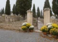 ’ingresso di un cimitero con crisantemi, come la navetta per il cimitero di Scicli. Immagine generata con intelligenza artificiale.