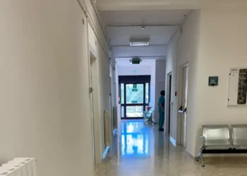 Corridoio del Pronto Soccorso di Modica con pavimento in marmo, panche in metallo e un'operatrice sanitaria in divisa verde