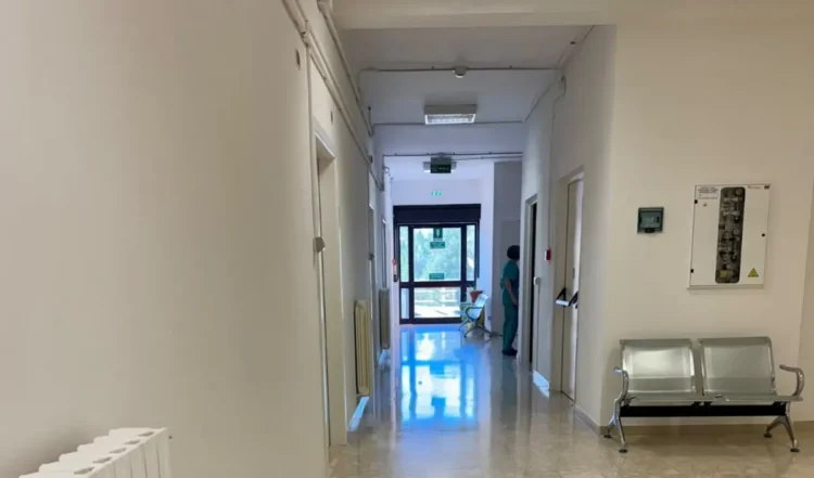 Corridoio del Pronto Soccorso di Modica con pavimento in marmo, panche in metallo e un'operatrice sanitaria in divisa verde