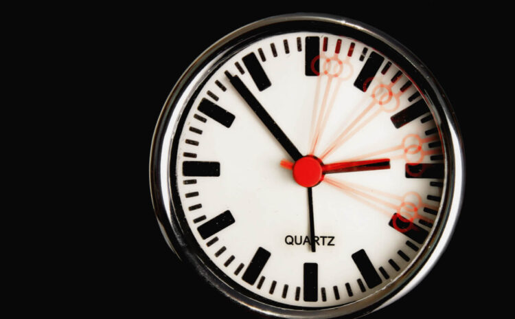 Orologio da parete al quarzo su sfondo nero: la lancetta rossa dei secondi è mossa, a evocare il cambio dell’ora solare