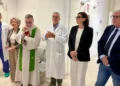 Sacerdote con stola verde, medici in camice e autorità nel corridoio della nuova area di osservazione dell'ospedale di Modica