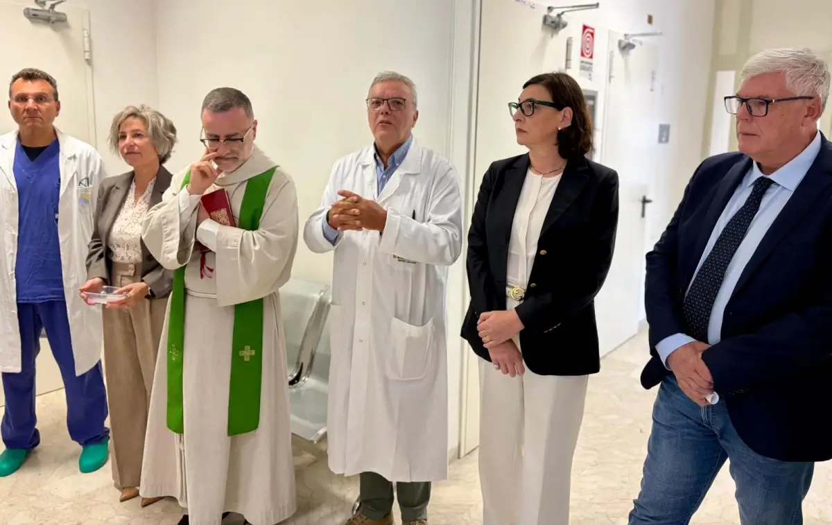 Sacerdote con stola verde, medici in camice e autorità nel corridoio della nuova area di osservazione dell'ospedale di Modica