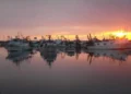 Pescherecci dei pescatori di Scoglitti ormeggiati nel porto al tramonto, con le sagome riflesse nell'acqua calma