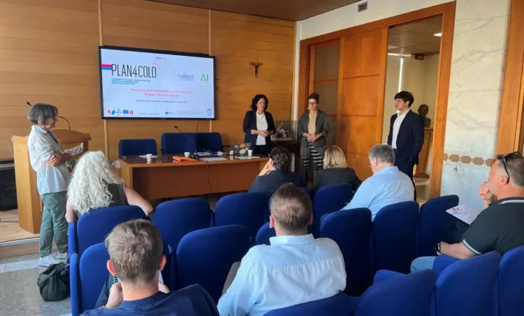 Sala riunioni con lo schermo di Plan4COLD su Ragusa, Modica e Vittoria, tre relatori in piedi e il pubblico seduto