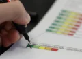 Una mano con un pennarello nero segna una crocetta sulla casella verde di una scala colorata in un questionario cartaceo