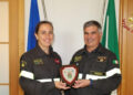 Una vigile del fuoco e il comandante dei vigili del fuoco di Ragusa reggono un crest davanti alle bandiere italiana ed europea