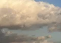 Grande nuvola bianca illuminata dal sole su un cielo azzurro, con nubi più scure nella parte bassa dell'immagine