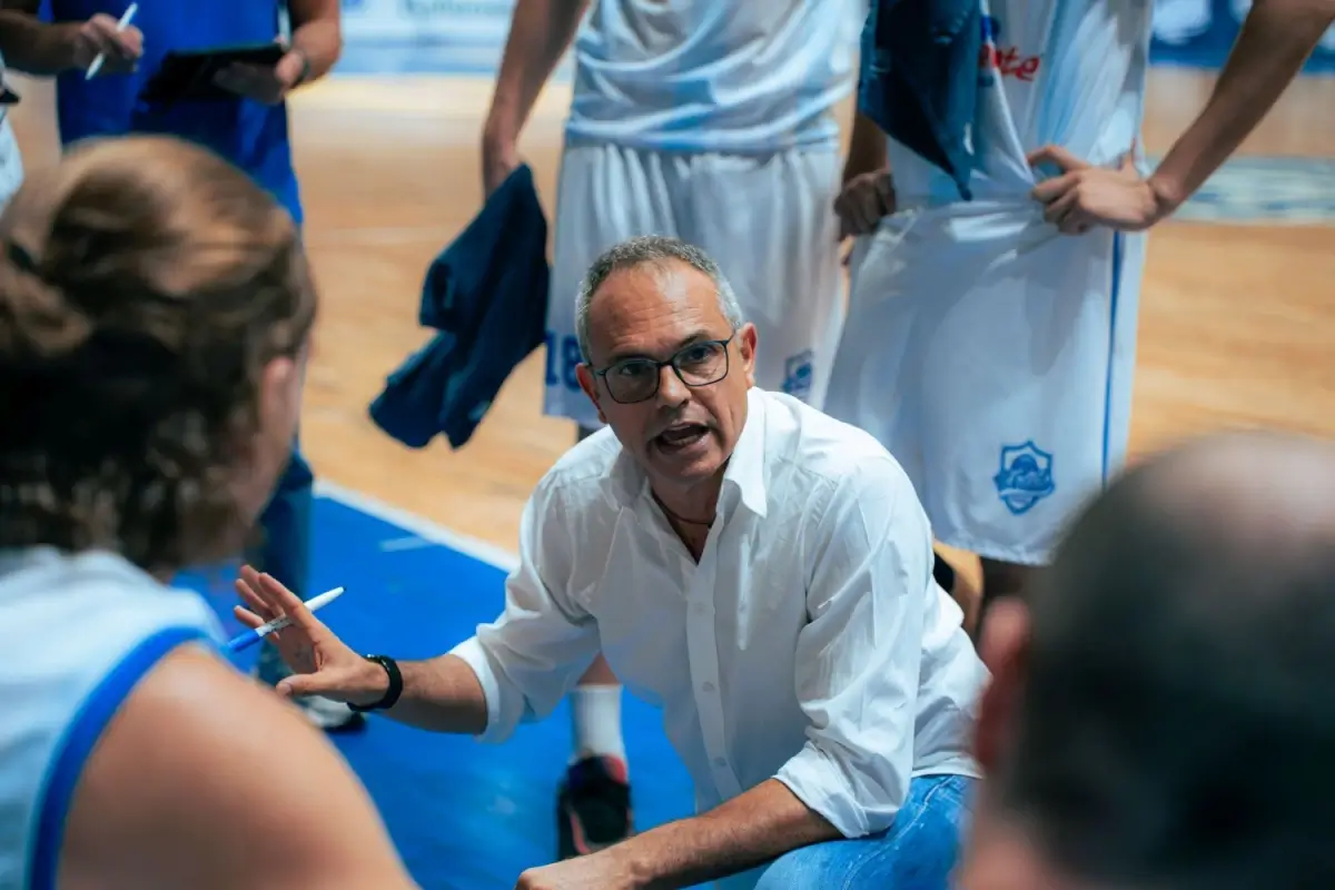 Gianni Recupido, coach della Virtus Ragusa, in camicia bianca parla alla squadra durante un timeout con un pennarello in mano
