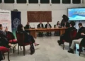 Relatori al tavolo del convegno Restanza a Modica, pubblico in sala e titolo dell’incontro proiettato sullo schermo