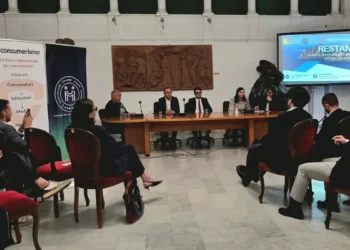 Relatori al tavolo del convegno Restanza a Modica, pubblico in sala e titolo dell’incontro proiettato sullo schermo