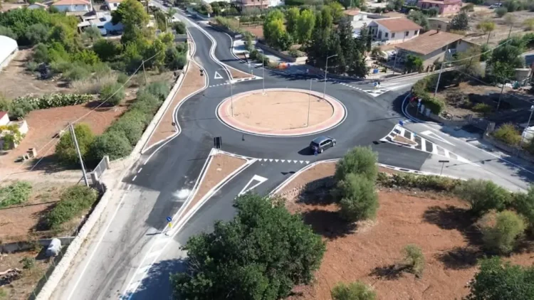 Vista aerea della rotonda della Madonnina a Santa Croce Camerina con aiuola centrale, pali della luce e un'auto in transito