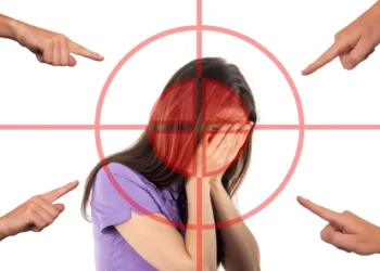Ragazza con il volto coperto dalle mani dentro un mirino rosso, indicata da quattro dita: lo stigma sulla salute mentale