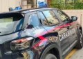 Fiancata di un’auto dei carabinieri con lampeggianti blu e numero 112, parcheggiata accanto a un marciapiede.