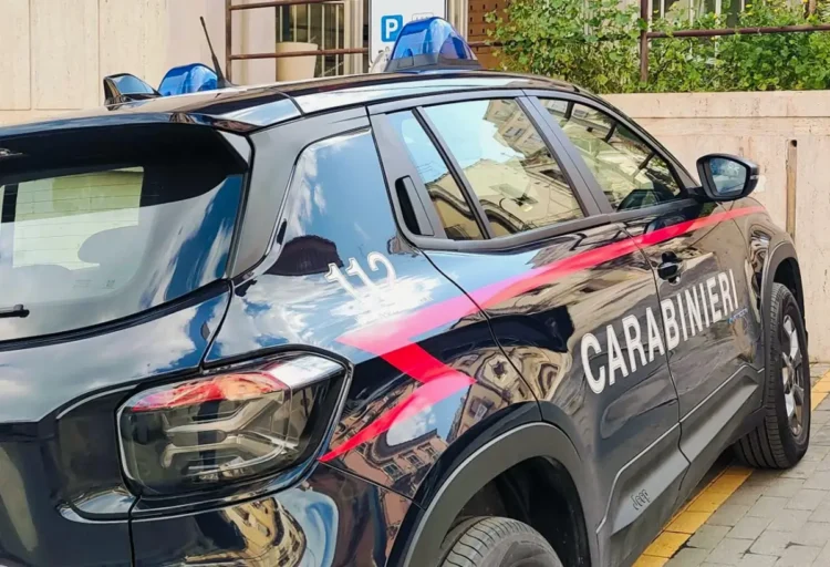 Fiancata di un’auto dei carabinieri con lampeggianti blu e numero 112, parcheggiata accanto a un marciapiede.