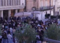 Studenti in sciopero a Ragusa radunati in piazza San Giovanni, tra gli ombrelloni di un bar e piante in primo piano