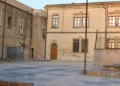 Cortile pavimentato con gradini e muretti tra due edifici storici a Chiaramonte Gulfi, scuole al centro delle critiche