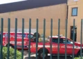 Pick-up dei vigili del fuoco e furgone di un'impresa edile nel cortile della scuola Matteotti, visti attraverso una cancellata