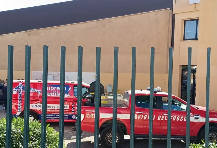 Pick-up dei vigili del fuoco e furgone di un'impresa edile nel cortile della scuola Matteotti, visti attraverso una cancellata