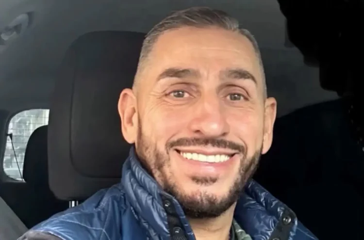 Sergio Sanzone sorridente in un selfie scattato in auto, con barba curata e piumino blu