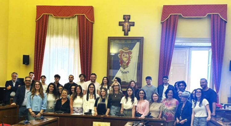 Volontari del servizio civile di Comiso in posa nell’Aula consiliare del Municipio, davanti al gonfalone della città