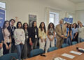 Giovani volontari del Servizio civile in posa nella sala riunioni di Confcommercio Ragusa, accanto a un tavolo e a roll-up blu